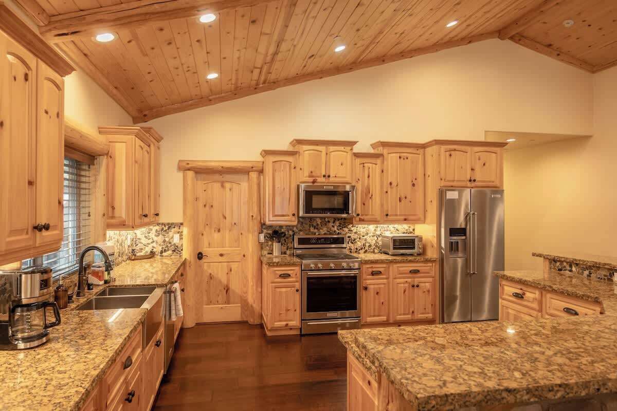 Eine Küche mit Holzschränken, Granit-Arbeitsplatten, Edelstahlgeräten und einer Holzziel.