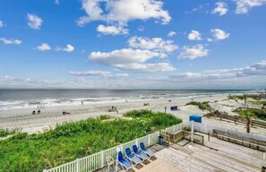 A beach view with a wooden boardwalk, beach chairs, and a clear sky. - Easton Pierfection, By the Garden City Pier (Murrells Inlet)