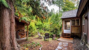 A rustic cabin with a stone pathway leading to a wooden deck, surrounded by dense forest. - Storybook Mt Hood Cabin • Wood Stove + Skylights (Rhododendron)