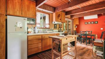Une cuisine avec des meubles en bois, un réfrigérateur blanc, un évier et un coin repas comprenant des chaises et une table.