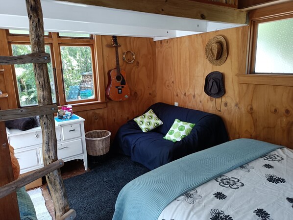 Um quarto acolhedor de madeira com uma cama, um violão e um chapéu na parede.