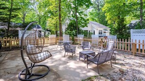 An outdoor patio with wicker furniture, a swing chair, and a small table. - 3 Bedroom Family Retreat in Ocean Pines! (Ocean Pines)