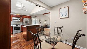 A modern kitchen with stainless steel appliances, a dining area with a glass table and chairs, and a living space with a sofa and decorative items. - 3 Bedroom Family Retreat in Ocean Pines! (Ocean Pines)