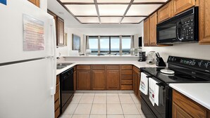 Una cucina moderna con mobili in legno, un forno a microonde nero e un'ampia finestra con vista.