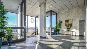 Un'ampia hall con grandi finestre, pareti in marmo e piante in vaso.