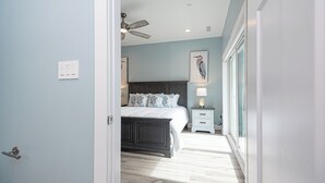 A bedroom with a bed, bedside table, lamp, and a ceiling fan.