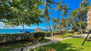 A tropical resort with a clear view of the ocean, palm trees, and a well-maintained garden with a pathway. - Saint Peter's Bay 208 - Chic Beachfront Condo (Battaleys)