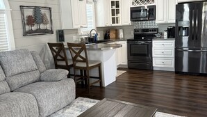 A modern kitchen with white cabinets, stainless steel appliances, and a wooden dining area.