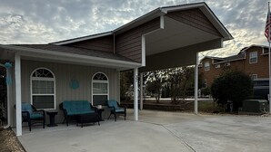 A covered outdoor seating area with chairs and tables, a building with a porch, and an American flag.
