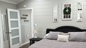 A bedroom with a large bed, a dresser, a nightstand, and a door with a mirror.