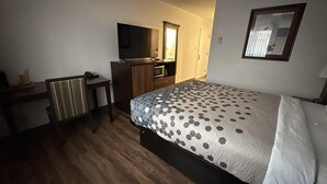 A hotel room with a bed, a desk, a chair, a TV, and a wardrobe. - Heritage Inn (Bellingham)