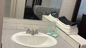 A bathroom with a white sink, a mirror, and a towel rack. - Heritage Inn (Bellingham)
