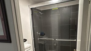 A compact bathroom with a toilet, a shower enclosure, and a visible door frame. - Heritage Inn (Bellingham)