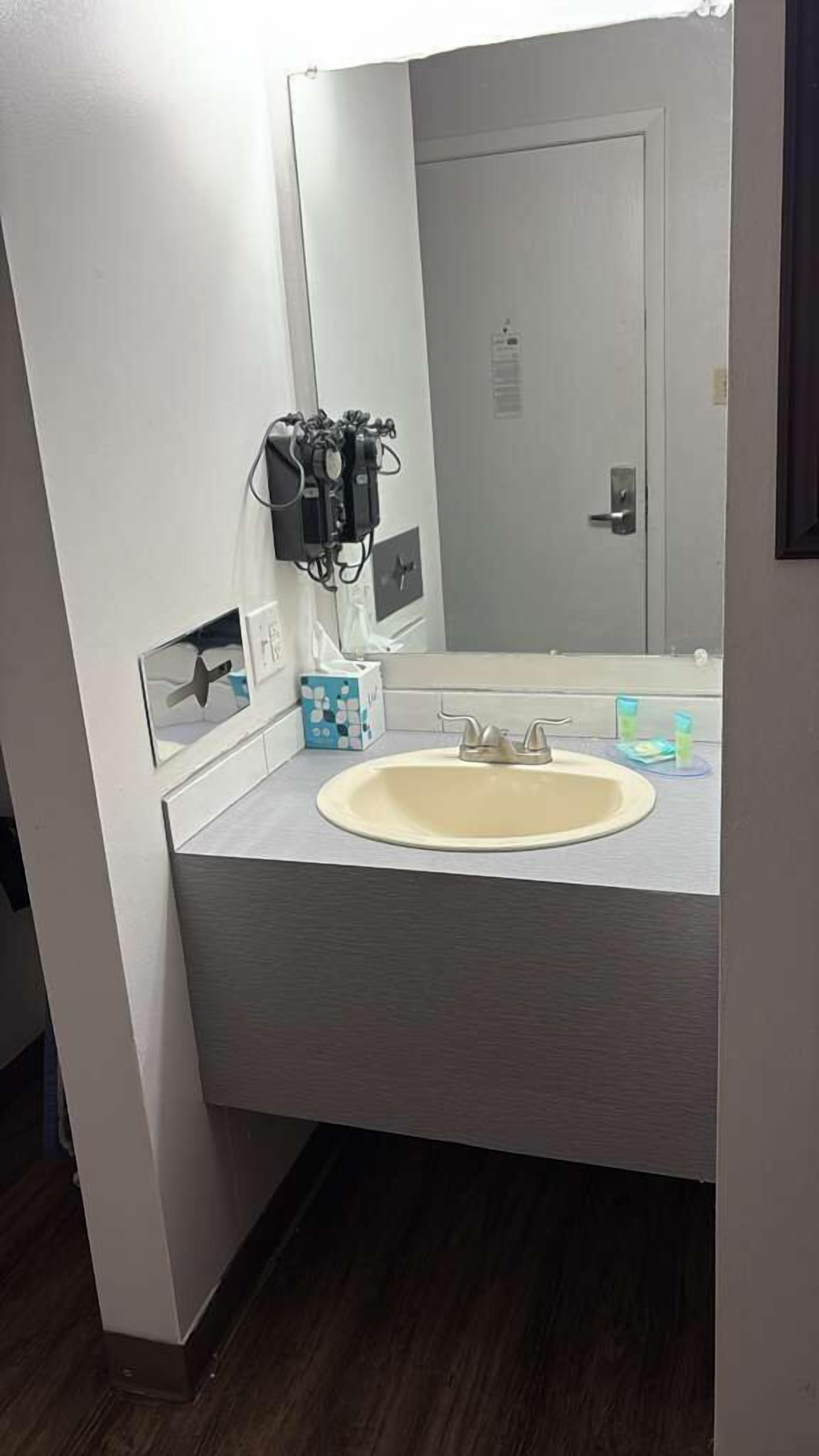 Ein Badezimmer mit Waschbecken, Spiegel und Luftreiniger an der Wand.