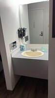Un baño con lavamanos, espejo y un purificador de aire de pared.