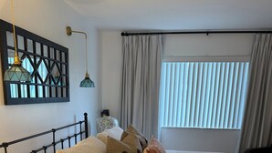 A neatly made bed with a headboard, a bedside table, and a lamp. - Ocean Village Beach Apartment on the Golf Course (Fort Pierce)