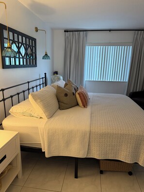 A neatly made bed with a headboard, a bedside table, and a lamp. - Ocean Village Beach Apartment on the Golf Course (Fort Pierce)