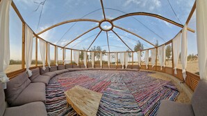 Une pièce circulaire offrant une vue imprenable sur le ciel, entourée de sièges confortables et agrémentée d’un tapis coloré.
