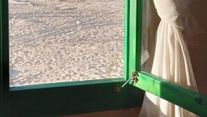 Une fenêtre donnant sur une plage et la mer.