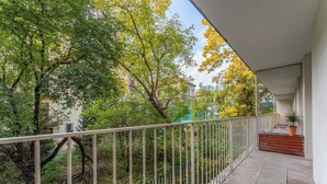 A balcony with a metal railing, a potted plant, and a wooden bench. - Cracow Home Harmony Apartment (Kraków)