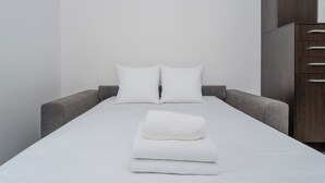 A modern hotel room with a neatly made bed, grey upholstered headboard, and a wooden wardrobe. - Cracow Home Harmony Apartment (Kraków)
