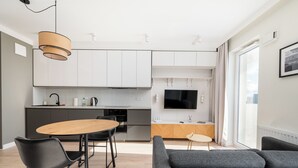 Une cuisine moderne avec des meubles blancs, une table à manger en bois et des chaises noires.