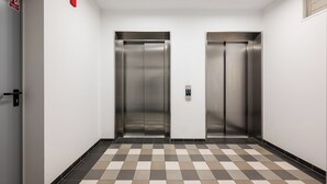 Un couloir avec deux ascenseurs, un système d’alarme incendie et un comptoir d’enregistrement.