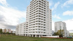 Un immeuble résidentiel à plusieurs étages, à l’aspect extérieur uniforme, doté de nombreux balcons et d’un toit plat.