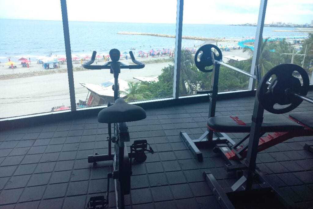 A gym with a view of a beach and ocean.