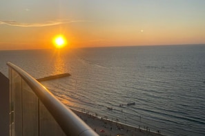 Un atardecer sobre el océano con una playa en primer plano.