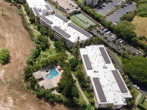 Oversigtsbillede af et hotel med flere bygninger, en tennisbane, en swimmingpool og en parkeringsplads.