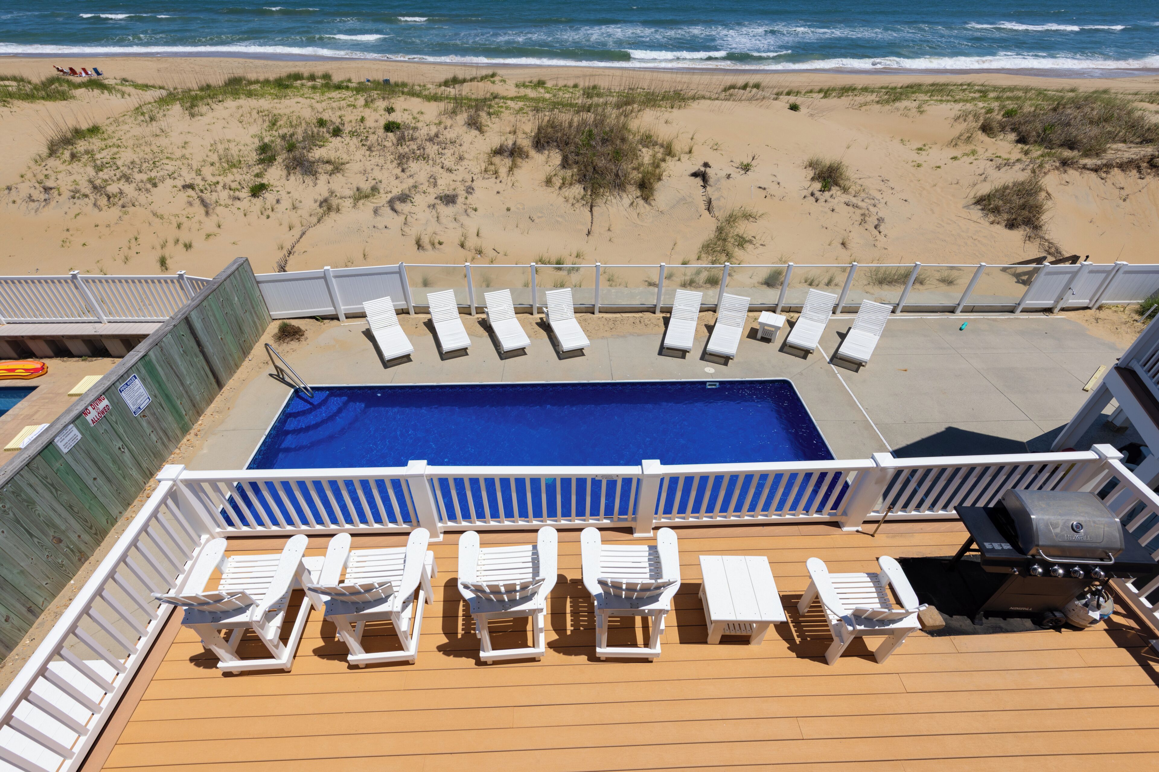 Zona de piscina con sillones de descanso y una parrilla en la cubierta de un crucero.