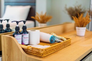 A bathroom counter with toiletries including bottles of shampoo and bath gel, a roll of toilet paper, and a blue hairdryer.