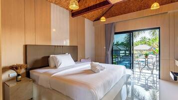 A modern hotel room with a large bed, wooden ceiling beams, and a view of a pool and palm trees.