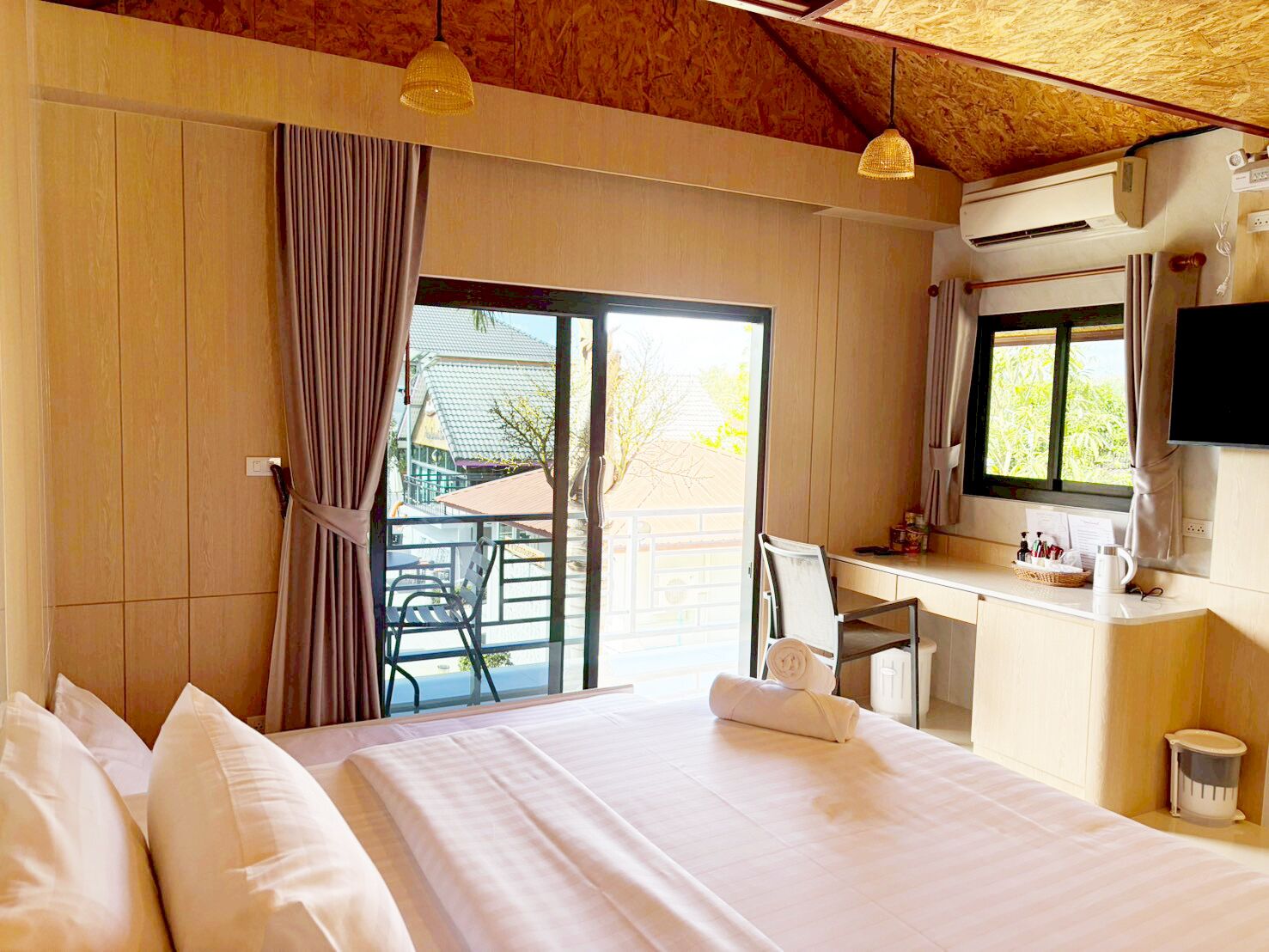 A hotel room with a bed, a desk, a chair, a TV, and a window with curtains.
