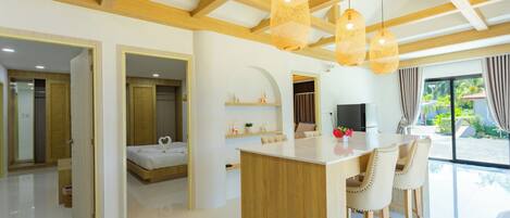A modern kitchen with a central island, wooden beams, and pendant lights.