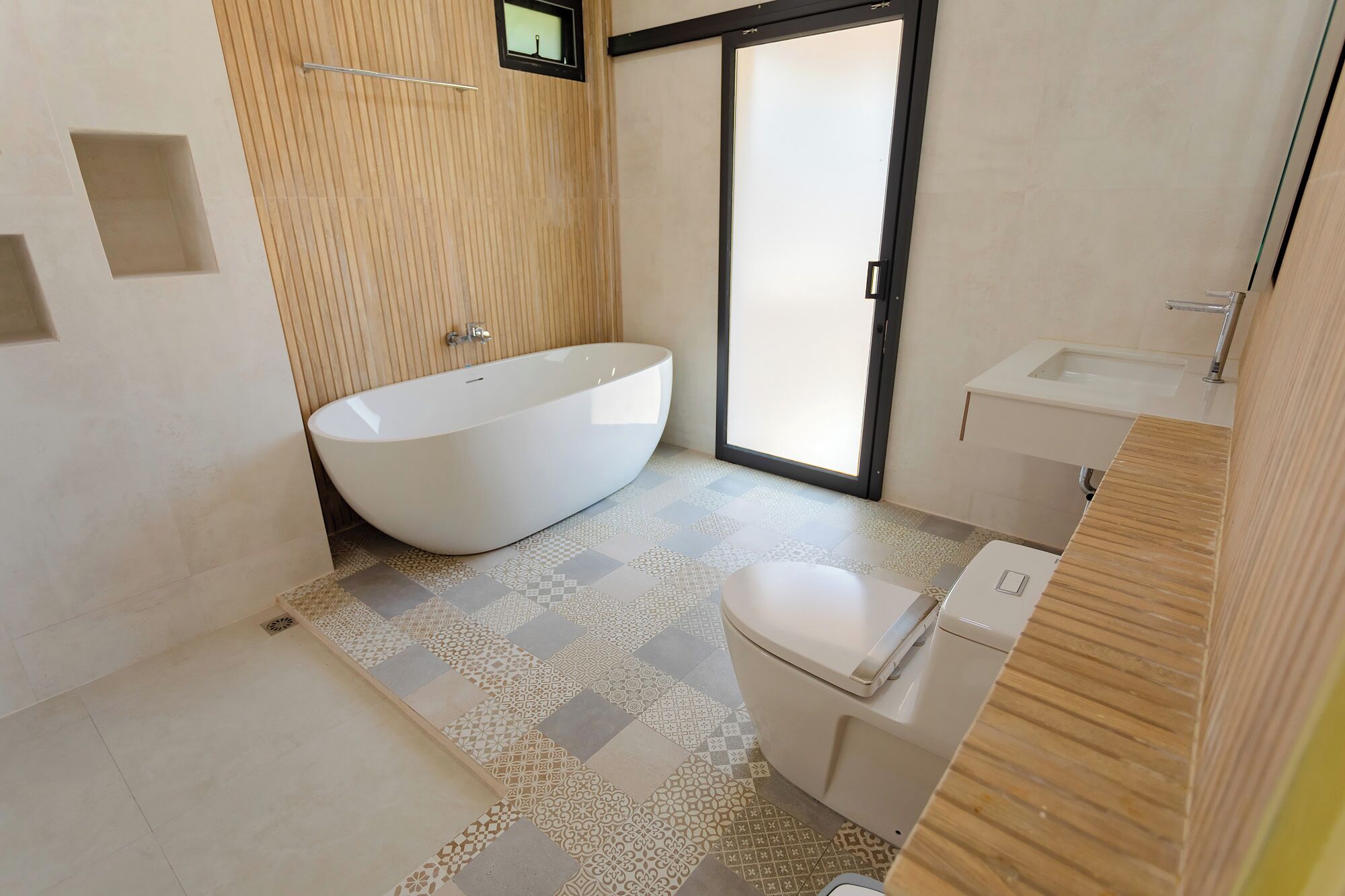 A modern bathroom with a freestanding bathtub, a toilet, and a sink.
