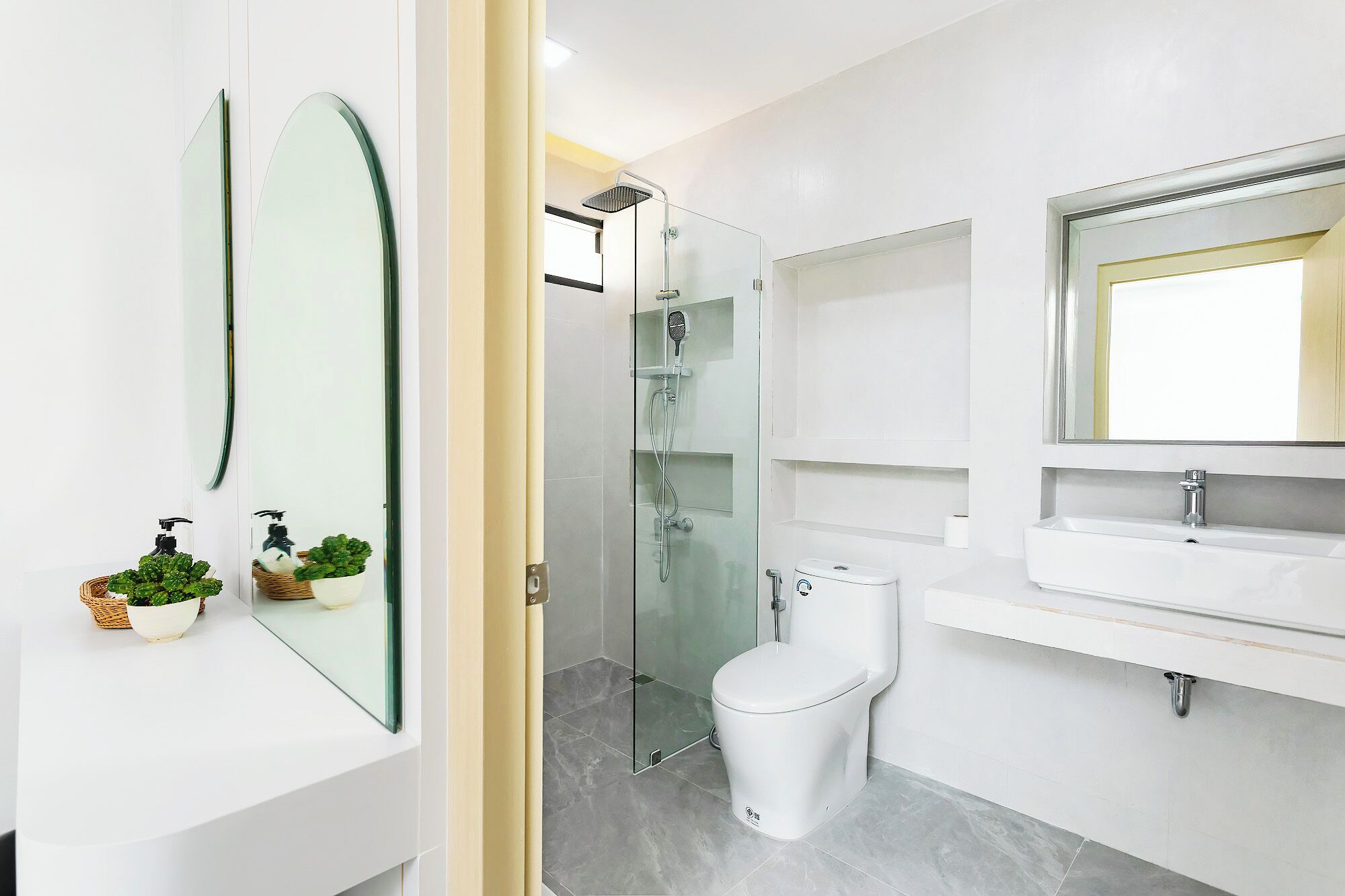 A modern bathroom with a glass shower enclosure, a toilet, and a sink with a mirror above it.