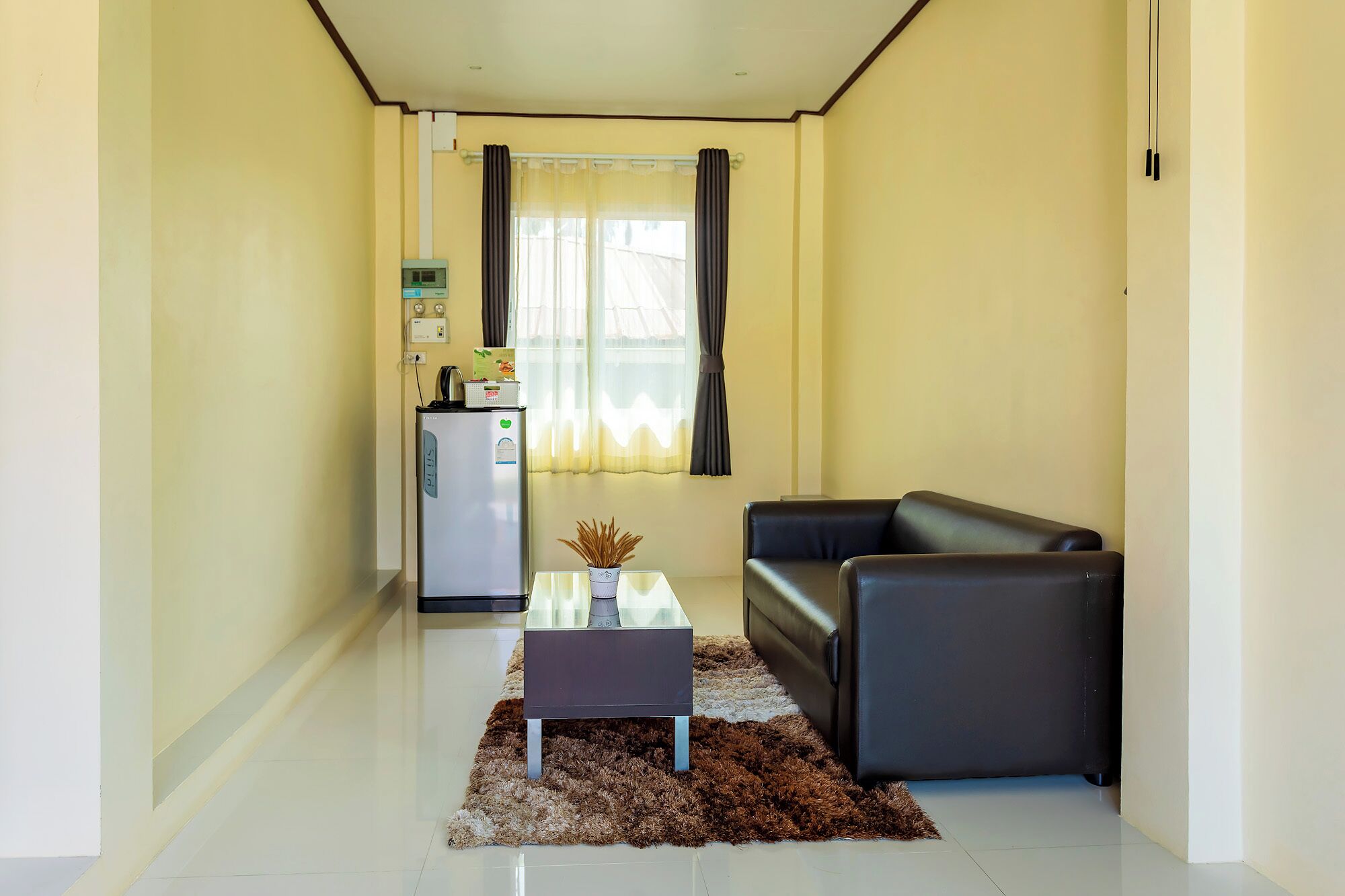 A compact living space with a sofa, a small table, and a refrigerator.