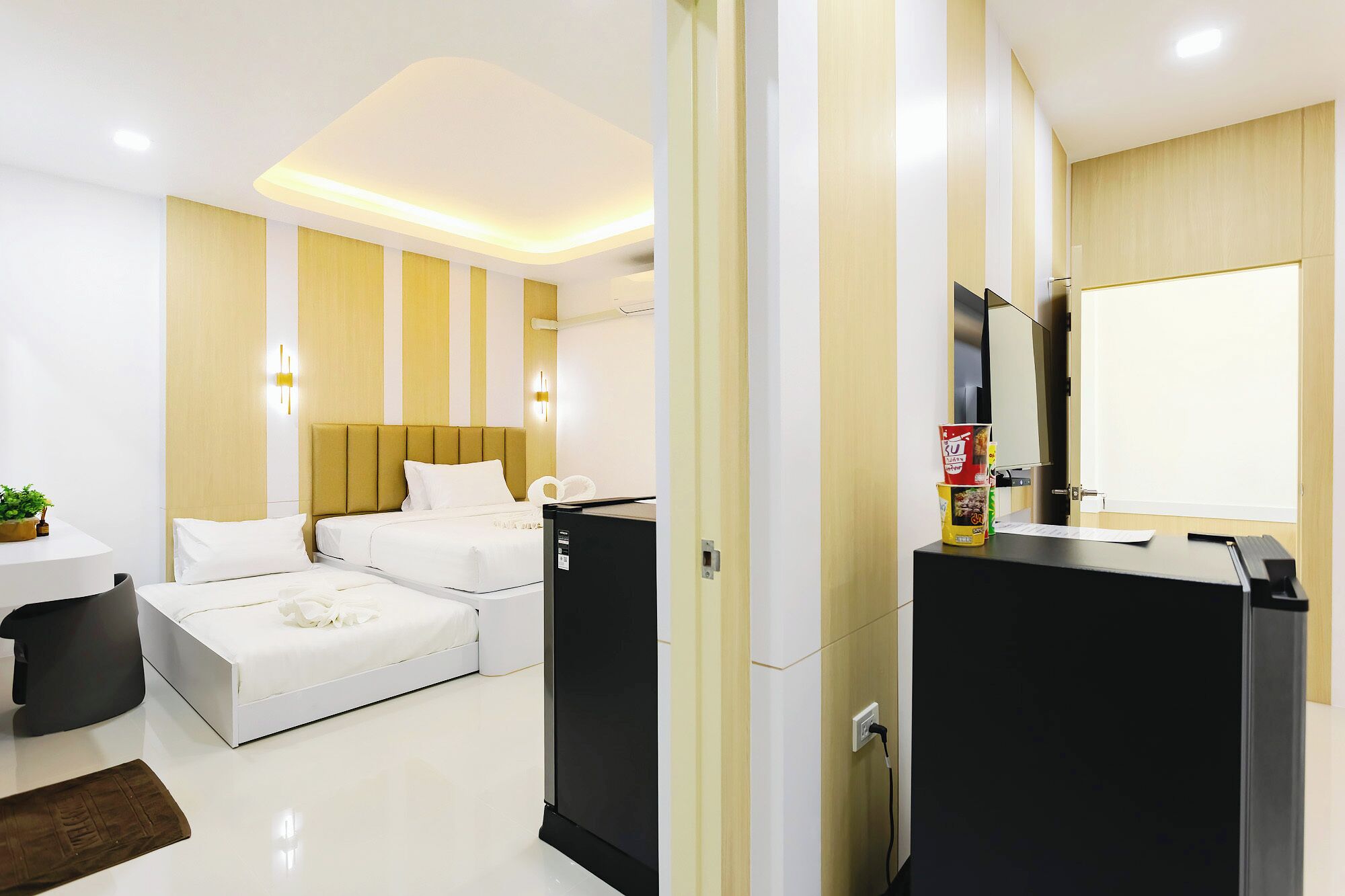 A modern hotel room with a bed, bedside table, and a desk with a computer.