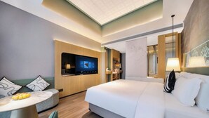 A modern hotel room with a large bed, a desk, a flat-screen TV, and a seating area with a round table and chairs. - BEIJING JIASHIDE HOTEL (Tongzhou)