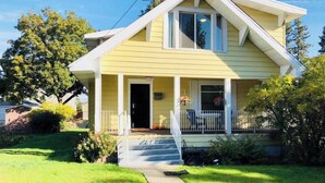 A yellow house with a front porch, a visible number '1911', and a clear sky. - The Perry Canary: Newly Renovated, Charming, Walk to Coffee and Restaurants (Spokane)