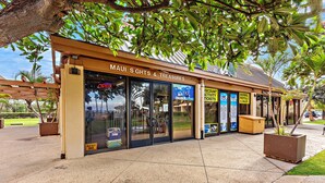 En butiksvisning med et skilt, der viser "Maui Sights & Treasures", og diverse reklamer for udlejning og aktiviteter.