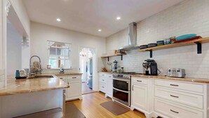 A modern kitchen with white cabinetry, a central island, and a brick backsplash. - Charming Spanish-Style Home in the Heart of Davis Shores (St. Augustine)