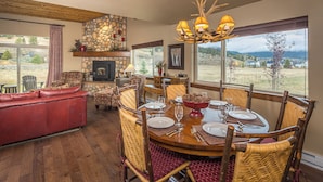 A dining area with a stone fireplace, wooden dining table, and chairs.