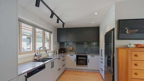 Eine moderne Küche mit weißen Schränken, einem eingebauten Backofen und einem großen Fenster.