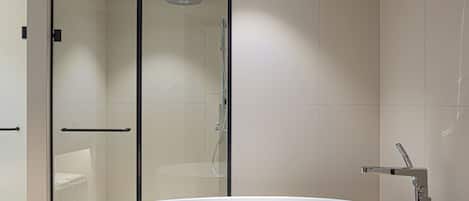 Un baño moderno con una bañera independiente, cabina de ducha de vidrio y ducha a pie.