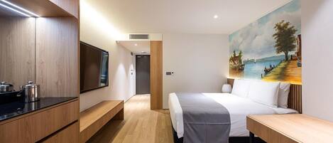A modern hotel room with a bed, a TV, a painting, and a wooden desk.