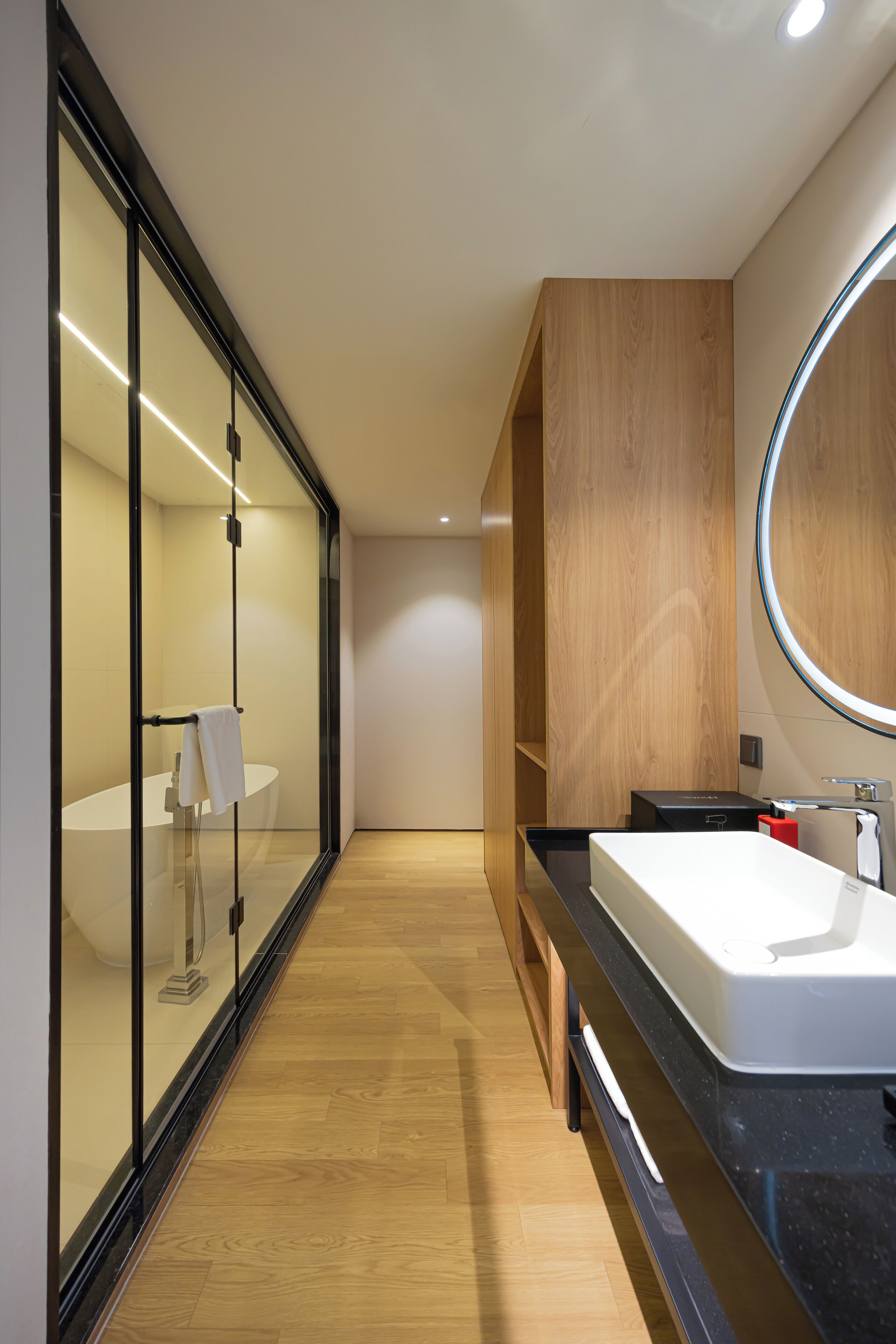 Een moderne badkamer met een grote spiegel, een witte wastafel en een douchecabine met glazen wanden.
