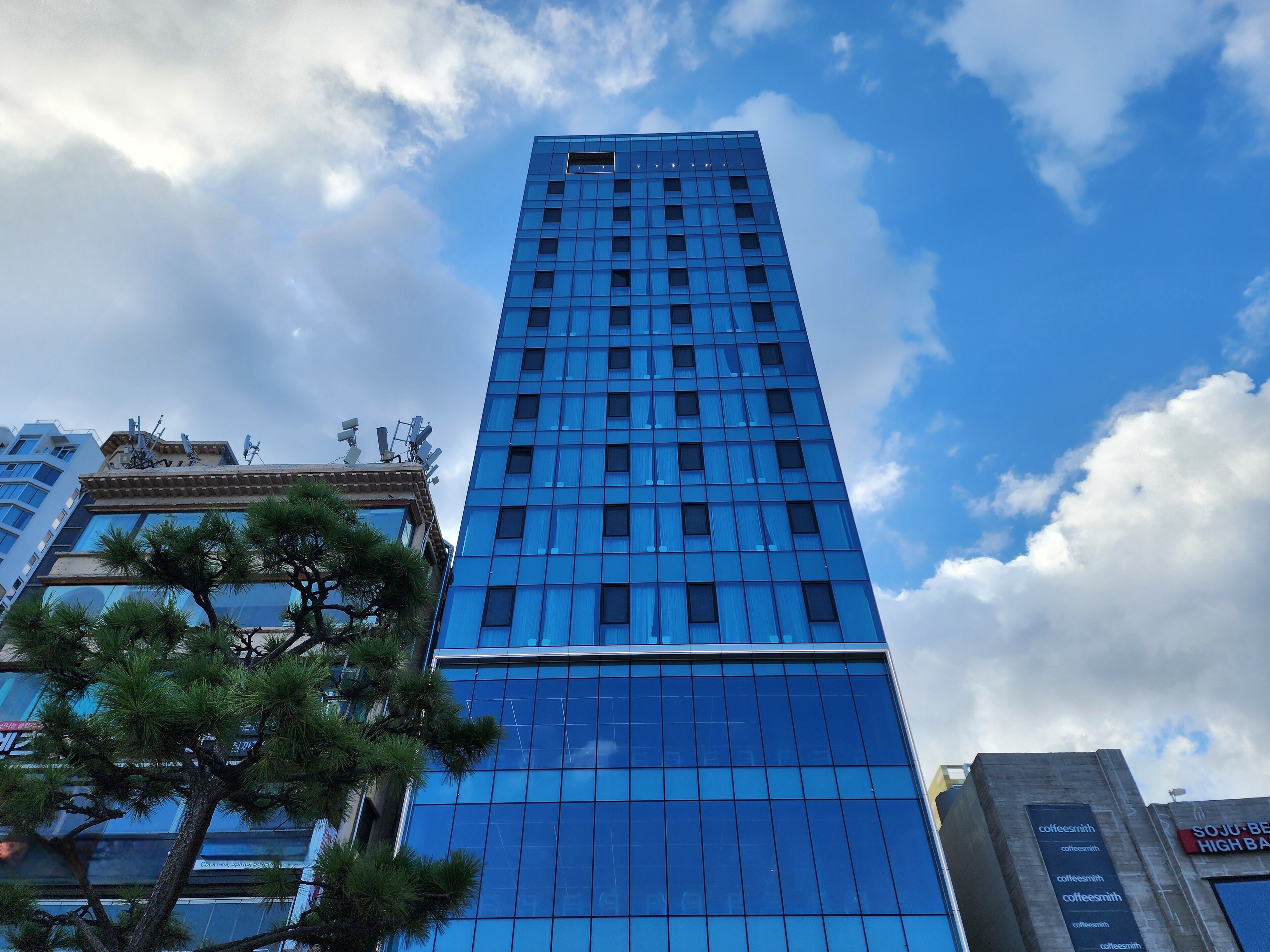 A tall, modern building with a glass facade and a clear sky in the background.